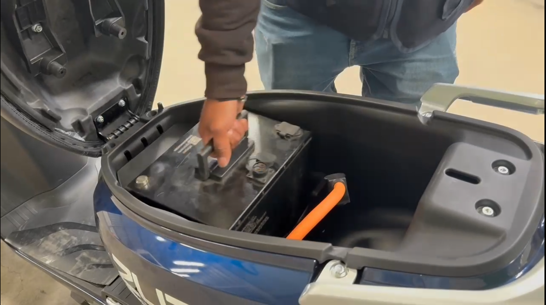 Usuario instalando una batería cargada en una moto ZUAP